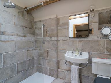 A bathroom with a shower area a pedestal sink a towel on the sink and a toilet at Pen Bont Home Farm in Upper Chapel near Builth Wells