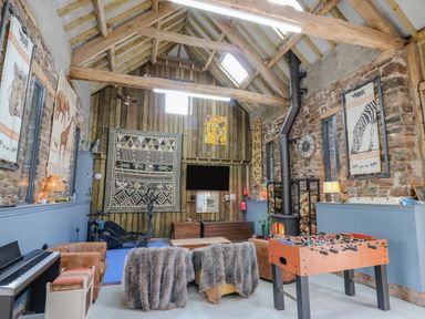 A recreational room with a foosball table a wood stove a piano and sports equipment at Pen Bont Home Farm Upper Chapel near Builth Wells