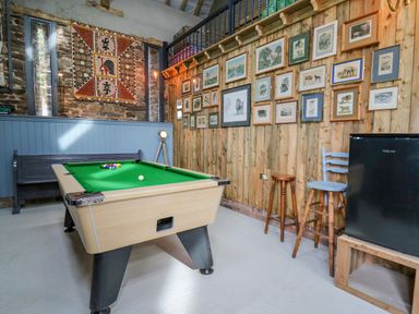 A room with a pool table a bench a mini fridge stools and framed pictures on wooden walls at Pen Bont Home Farm in Upper Chapel near Builth Wells