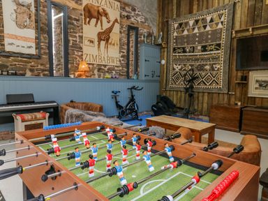 A game room with a foosball table exercise bikes a piano and animal artwork at Pen Bont Home Farm in Upper Chapel near Builth Wells