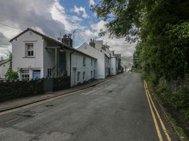 A street with white buildings on the left and trees on the right at Style Cottage in Keswick