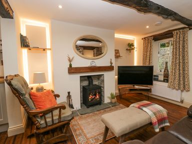 A living room with a rocking chair a TV and a fireplace at Style Cottage in Keswick