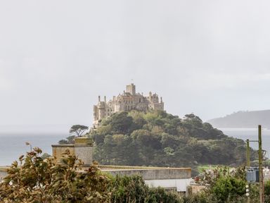 A castle on a hill surrounded by trees overlooking the sea at Atlantic Reach in Marazion