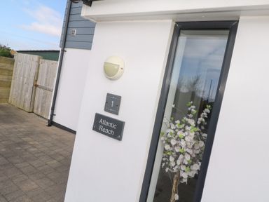 Exterior corner of a white building with a window showing flowers inside a glass vase at Atlantic Reach Marazion