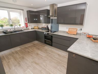 A kitchen with grey cabinets a double sink a stove an oven and countertop appliances at Atlantic Reach in Marazion