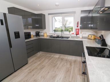 A kitchen with grey cabinets a refrigerator microwave coffee maker toaster and a window at Atlantic Reach in Marazion