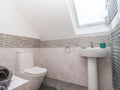 A bathroom with a toilet sink and towel rack under a skylight window at Atlantic Reach in Marazion