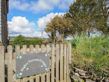 A wooden gate with a sign reading Higher Treveria Cottages No 2 and surrounding trees and greenery at Skylarks in No Mans Land near Looe
