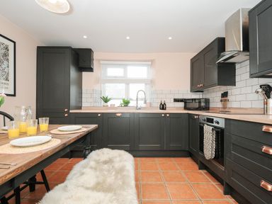 A kitchen with black cabinets wooden countertops and a wooden dining table with plates and glasses at Skylarks No Mans Land near Looe