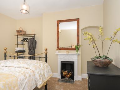 A bedroom with a metal bed a mirror above a fireplace and a plant on a dresser at Skylarks in No Mans Land near Looe