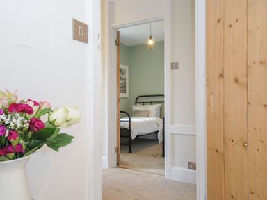 A hallway leading to a bedroom with a metal bed frame and a hanging light at Skylarks in No Mans Land near Looe