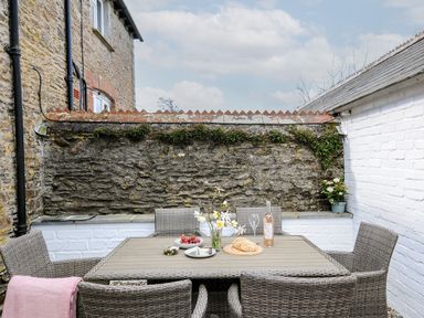 An outdoor patio with a table set with food and drink and wicker chairs at Skylarks in No Mans Land near Looe