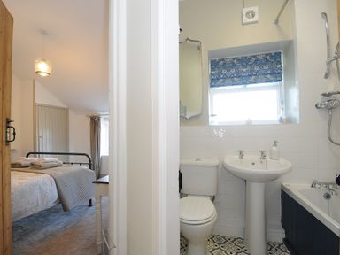 A bedroom with a bed and a bathroom with a toilet and sink at Skylarks in No Mans Land near Looe