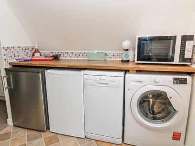 A utility room with a small fridge freezer dishwasher washing machine and microwave at No 51 Valley Lodges Honicombe Manor near Gunnislake
