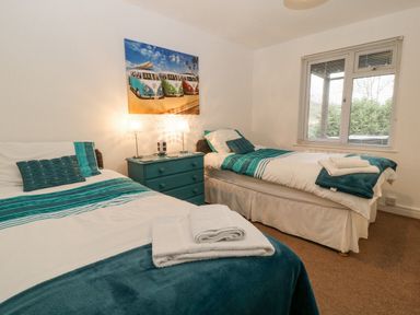 A bedroom with two single beds a teal chest of drawers between the beds and a window at No 51 Valley Lodges Honicombe Manor near Gunnislake
