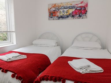 A bedroom with two single beds with red blankets and white towels at No 51 Valley Lodges in Honicombe Manor near Gunnislake