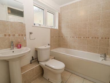 A bathroom with a pedestal sink toilet and bathtub with tiled walls at No 51 Valley Lodges Honicombe Manor near Gunnislake