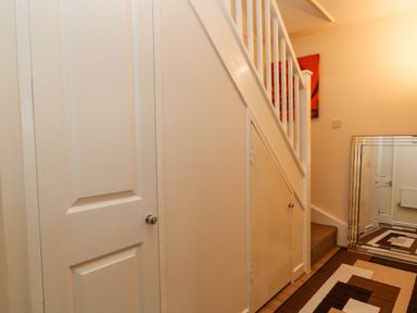 A hallway with a staircase and two closed doors with a large mirror and a patterned carpet at No 51 Valley Lodges in Honicombe Manor near Gunnislake