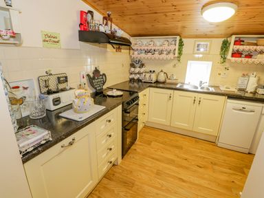 A kitchen with cream cabinets a stove toaster kettle and dishwasher at Cartron Cottage Ballintubber County Mayo
