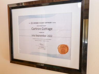 A framed certificate awarded to Cartron Cottage by the Sykes Holiday Cottages family for July to September 2022 at Cartron Cottage in Ballintubber County Mayo