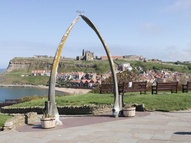 A whale bone arch with benches overlooking a coastal town and historic abbey at Stokers Rest in Whitby