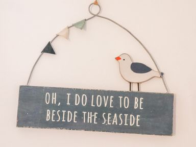 A wall hanging with a bird figure and text saying oh I do love to be beside the seaside at Stoker's Rest in Whitby