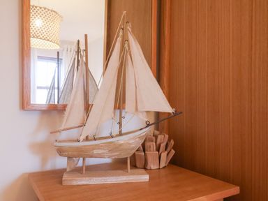 A model sailboat on a wooden table with a mirror and a light fixture in the background at Stoker's Rest in Whitby