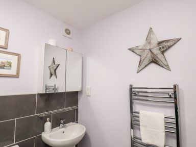 A bathroom with a sink mirror cabinet towel rail and star wall decoration at Stoker's Rest in Whitby