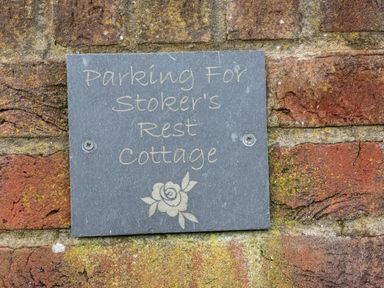A grey parking sign with text mounted on a red brick wall at Stoker's Rest in Whitby