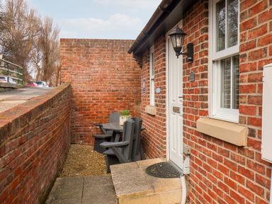 A brick exterior with a small patio area containing black chairs and a table at Stoker's Rest in Whitby