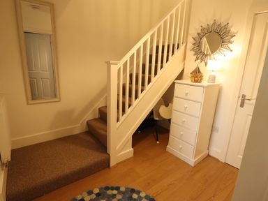 A stairway with carpeted steps a white chest of drawers a round mirror a lamp a chair and a wall mirror at Stoker's Rest in Whitby