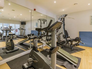 A gym room with exercise bikes treadmills weight machines and large mirrors at Apartment 18 Burgh Island Causeway Bigbury-On-Sea