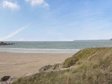 A beach with sand and ocean waves viewed from a grassy hill at Apartment 18 Burgh Island Causeway Bigbury-On-Sea
