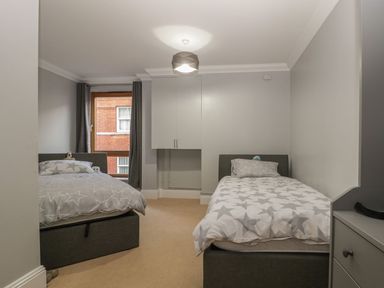 A bedroom with two single beds and a window with curtains at Townbridge Apartment in Weymouth