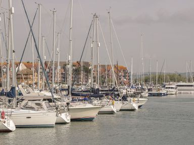 A marina with sailboats docked in the water and buildings in the background at Townbridge Apartment in Weymouth