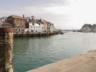 A harbor with boats docked near buildings and a pub called The George Inn at Townbridge Apartment in Weymouth