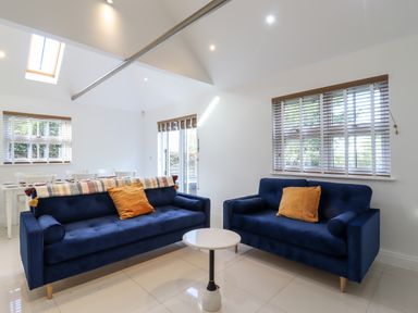 A living room with two blue sofas and a small round white table at Dreamwood Lodge in Keston near Leaves Green