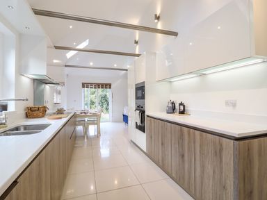 A kitchen with wooden cabinets white countertops and dining table at Dreamwood Lodge in Keston near Leaves Green