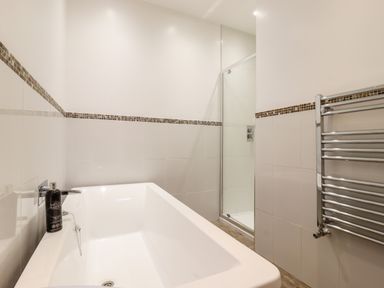 A bathroom with a bathtub a shower cubicle and a towel radiator at Dreamwood Lodge in Keston near Leaves Green