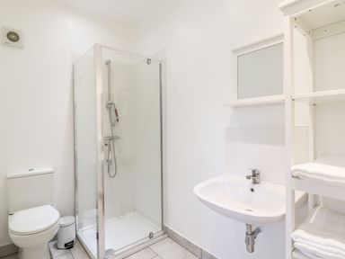 A bathroom with a toilet shower enclosure sink and shelves with towels at Dreamwood Lodge in Keston near Leaves Green