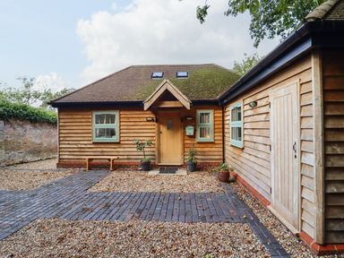 A wooden house with a small porch door and two potted plants in front at Dreamwood Lodge in Keston near Leaves Green