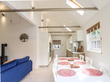 A kitchen and dining area with a white table and colorful placemats near windows at Dreamwood Lodge in Keston near Leaves Green