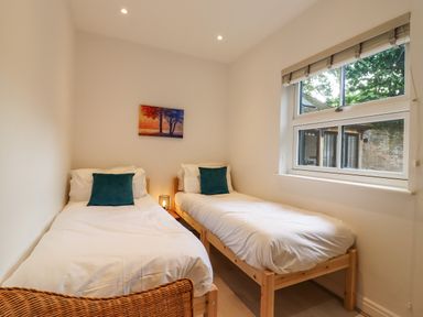 A bedroom with two single beds with white bedding and teal pillows a window and a painting on the wall at Dreamwood Lodge in Keston near Leaves Green