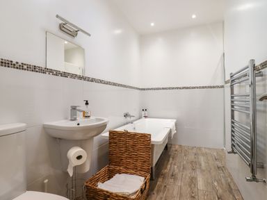 A bathroom with a sink toilet bathtub wicker basket and towel rack at Dreamwood Lodge in Keston near Leaves Green