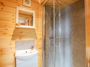 A bathroom with a sink mirror and glass shower enclosure at The Hideaway Pod in Rhoslan near Criccieth