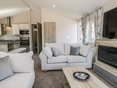 A living room with sofas cushions coffee table and wall mounted television at Parkers Place in Carnforth