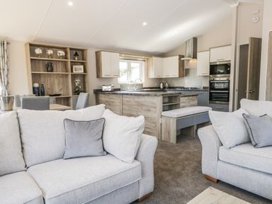 A living room with two sofas and a kitchen with cabinets and an island at Parkers Place in Carnforth