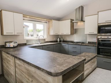 A kitchen with grey countertops white and grey cabinets a toaster kettle and oven at Parkers Place in Carnforth