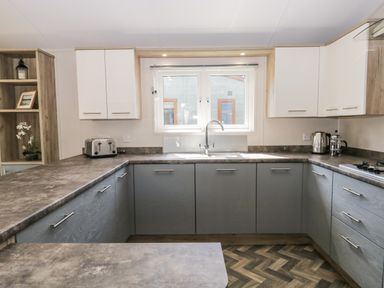 A kitchen with white upper cabinets grey lower cabinets a toaster kettle and coffee press on the counter at Parkers Place in Carnforth