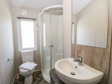 A bathroom with a toilet a glass shower enclosure and a sink with a mirror at Parkers Place in Carnforth